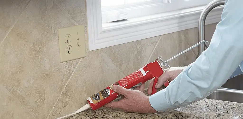 Handyman applying caulk along a kitchen backsplash and countertop seam in Allentown, PA