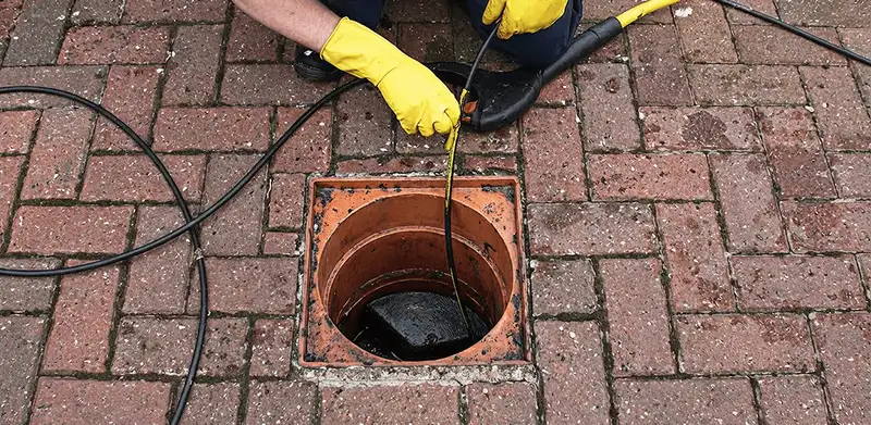 Drain cleaning technician using a drain snake to clear a clogged drain in Allentown, PA