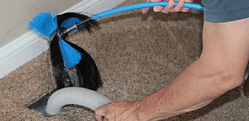 Dryer vent cleaning technician brushing lint from a vent line in Allentown, PA