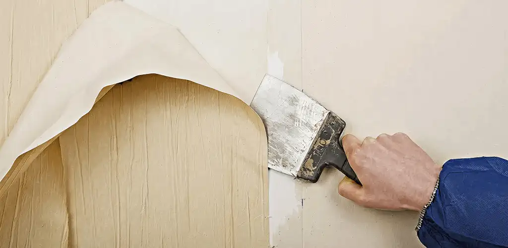 Handyman removing wallpaper with a scraper for wall preparation in Allentown, PA