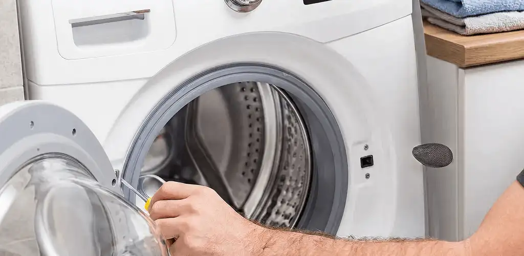 Handyman repairing a front-load washing machine and inspecting the drum in Allentown, PA