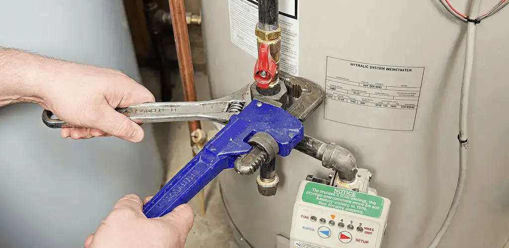 Water heater repair technician tightening the shutoff valve and supply line in Allentown, PA